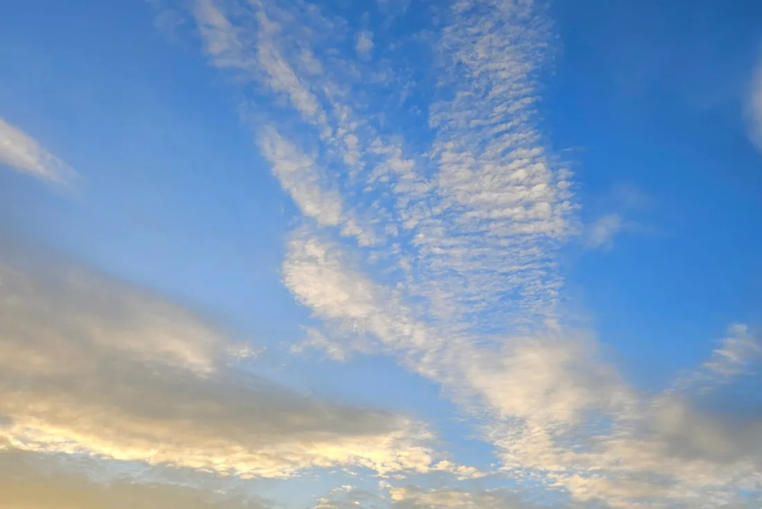 Himmel mit blauen und goldenen Farbtönen, durchzogen von weißen, wolkigen Formationen, die an Engelsflügel erinnern könnten.